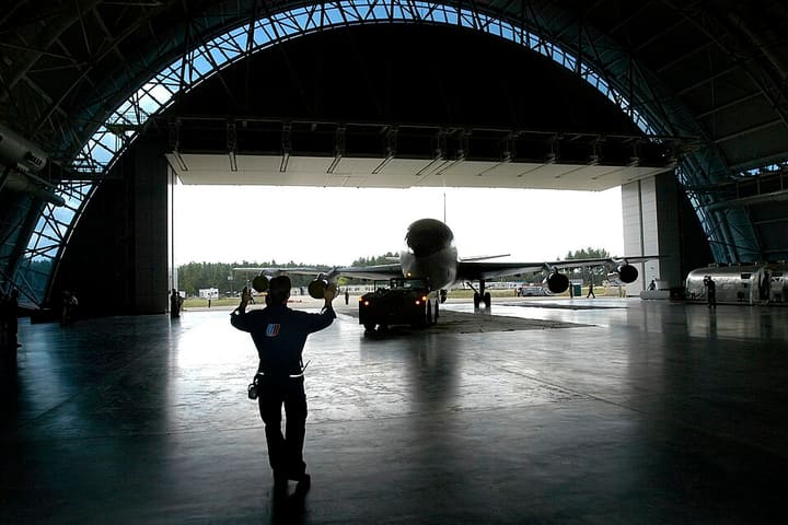A jet airliner framed by the open doors of a hangar