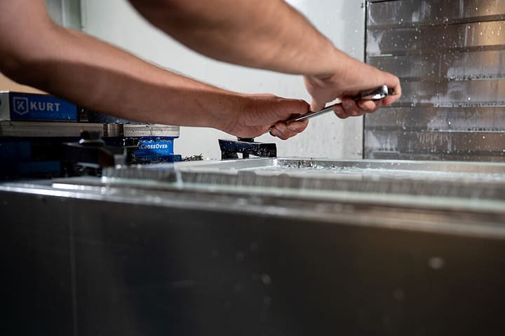 A machinist clamping a part in a milling machine vice